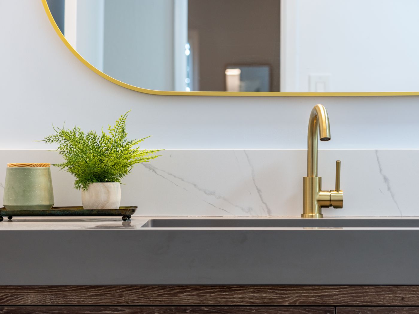 Detalle de baño con encimera de piedra y grifería dorada